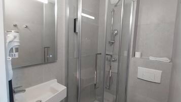 Ein modernes Badezimmer mit einer Duschkabine, einem weißen Waschbecken und einer Toilette.