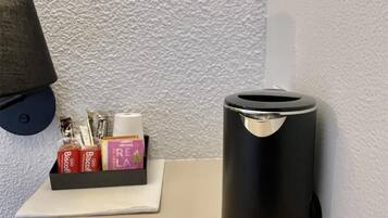 Una mesa pequeña con un cesto de basura negro y una caja de artículos de tocador.
