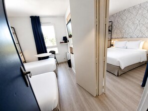 A hotel room with a bed, a desk, a chair, a small table, and a window with curtains. - Kyriad La Fleche (La Flèche)