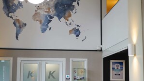 A reception area with a world map, a reception desk, a seating area with a chair and table, and a potted plant.