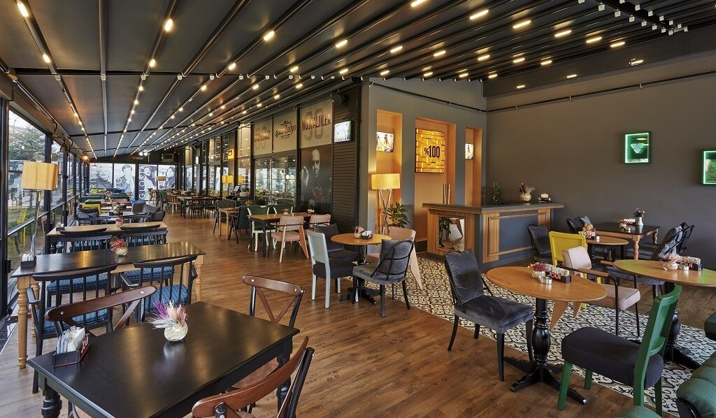 Un restaurante moderno con una barra alargada, varias zonas de estar y amplios ventanales que ofrecen vistas.