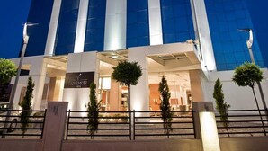 Een hoog hotel met een opvallend "ANEMON" bord aan de bovenkant, met een moderne glazen gevel en een symmetrisch ontwerp.