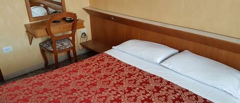Una habitación de hotel con una cama, un escritorio con una silla y un espejo.