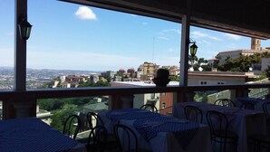 A terrace with tables and chairs, overlooking a cityscape with buildings and a distant view of the countryside. - Grande Albergo Abruzzo (Chieti)