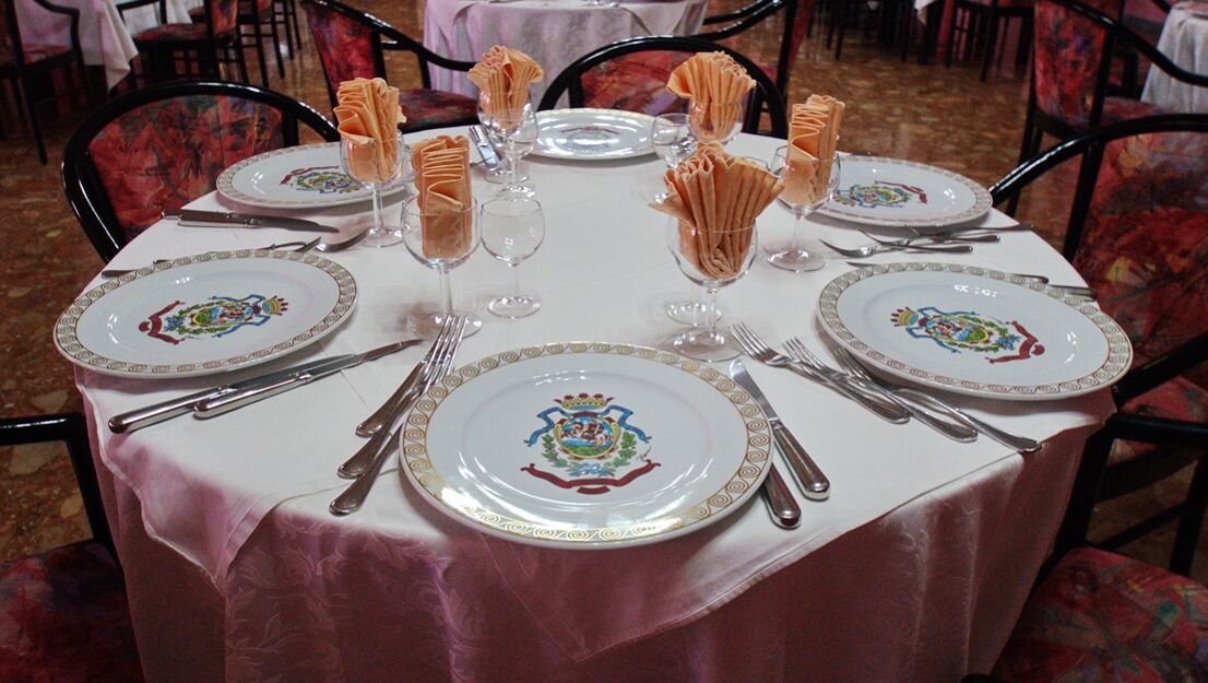 A dining table set with plates, cutlery, and folded napkins.