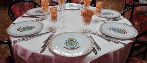 Una mesa de comedor dispuesta con platos, cubiertos y servilletas dobladas.