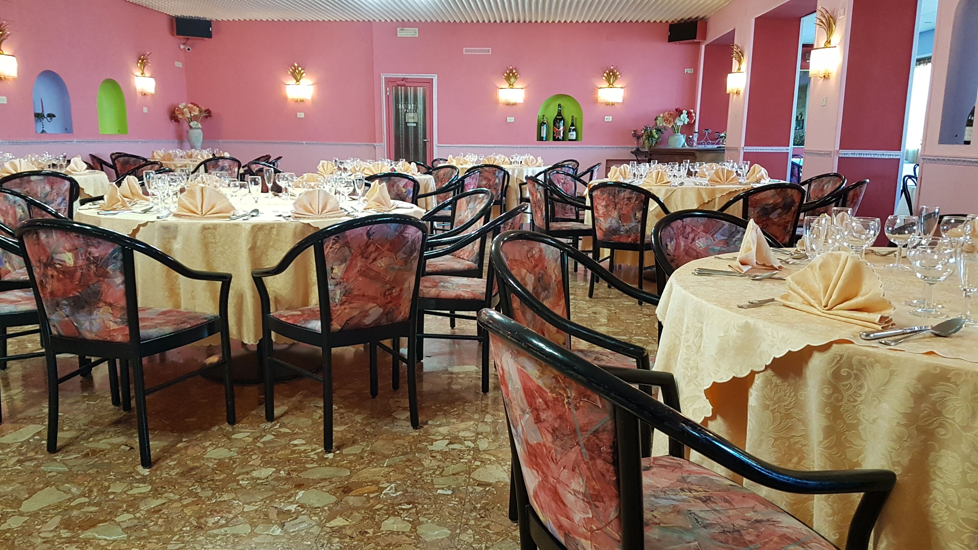 Zona pranzo con tavoli rotondi, sedie e pavimento piastrellato.