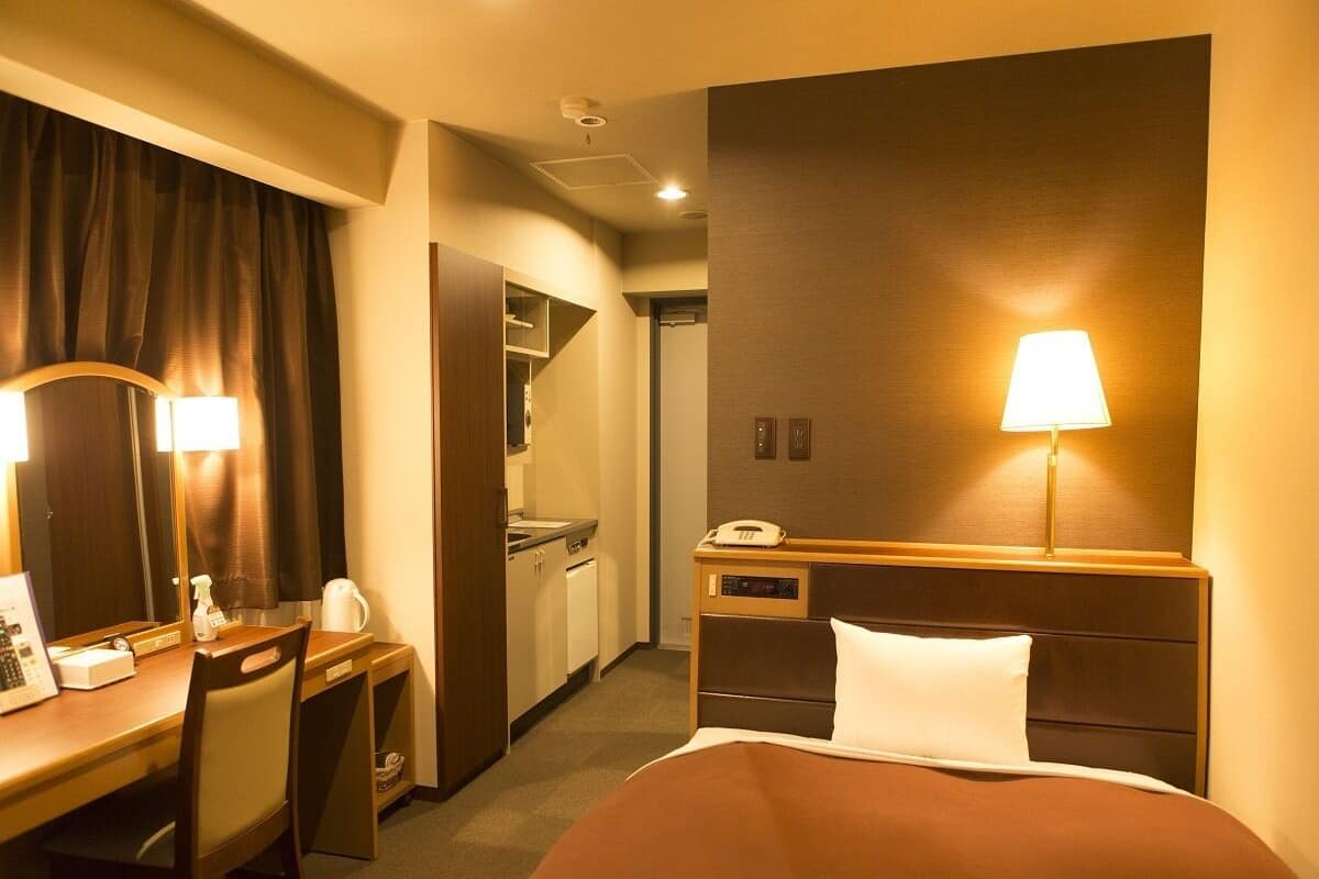 Ein Hotelzimmer mit Bett, Schreibtisch, Stuhl und einer Küchenzeile.