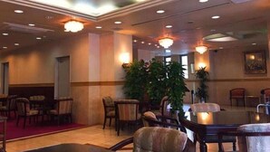 A hotel lobby with a chandelier, seating area, and a large plant. - Nissin Namba Inn (Osaka)