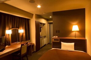 Habitación de hotel con cama, escritorio, silla y dos lámparas de noche.