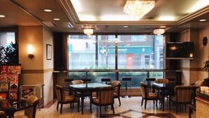 A hotel lobby with a checkered floor, tables, chairs, a chandelier, a TV, and a view of the outside. - Nissin Namba Inn (Osaka)