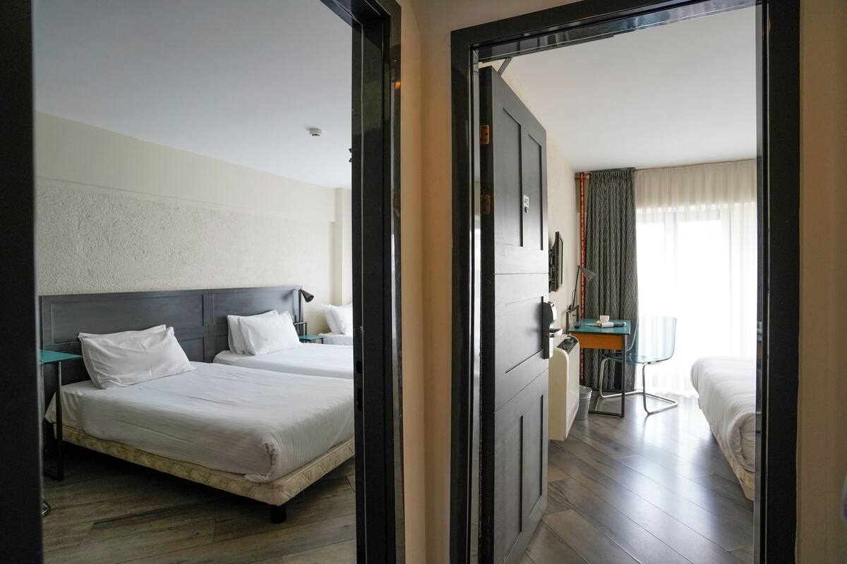 A hotel room with two beds, a desk, and a chair.