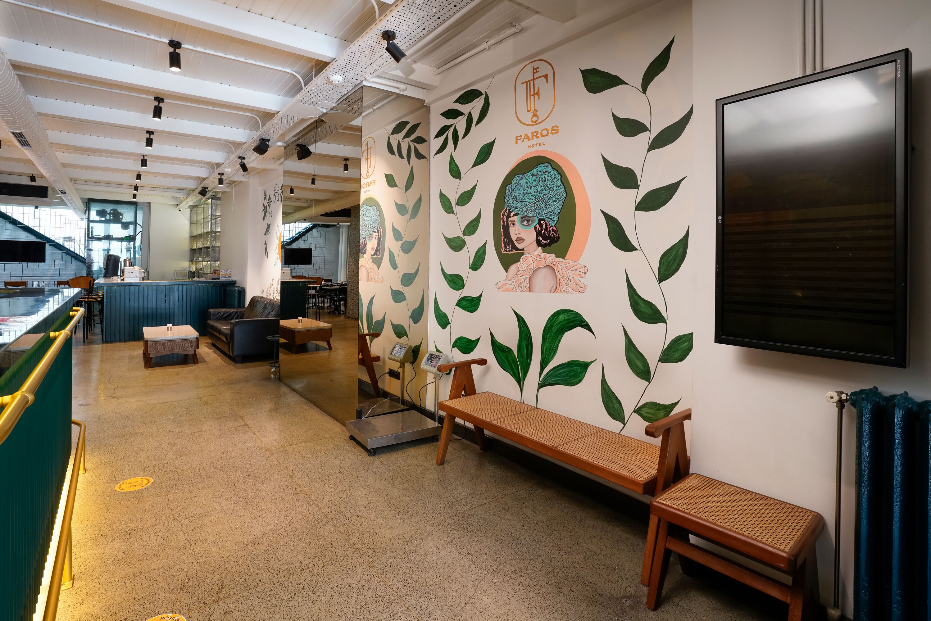 A hotel lobby with a reception desk, seating area, and a wall with a mural.