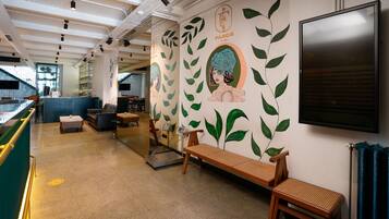 A hotel lobby with a reception desk, seating area, and a wall with a mural.