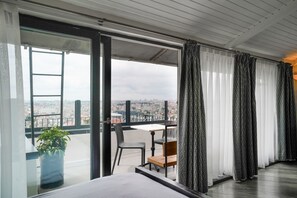 A balcony with a table and chairs, a potted plant, and a view of the city. - Faros Hotel Taksim (Istanbul)