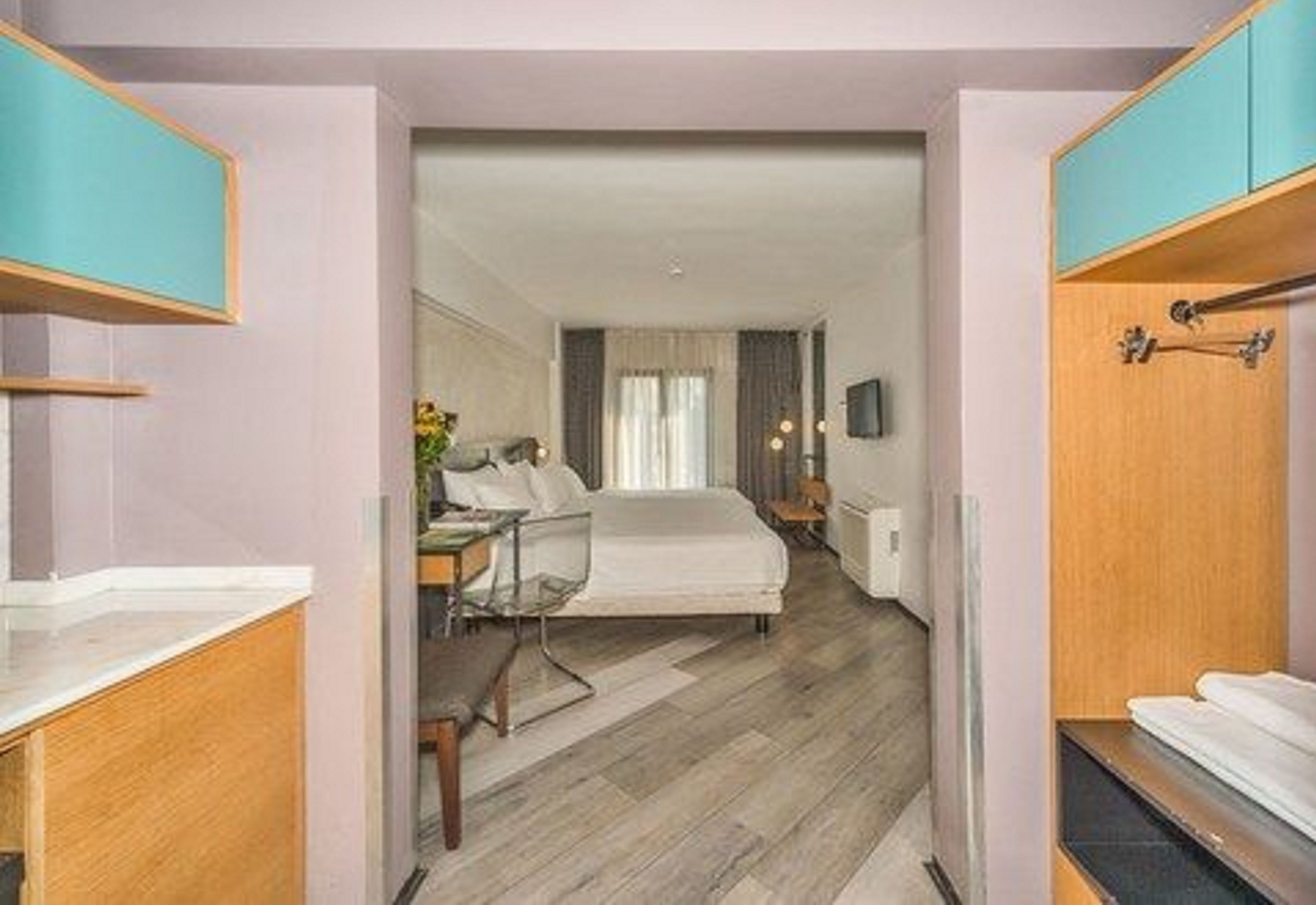 A hotel room with a bed, a desk, and a wardrobe.