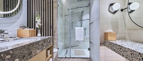 A modern bathroom with a glass-enclosed shower, a marble vanity, and a geometric patterned floor.