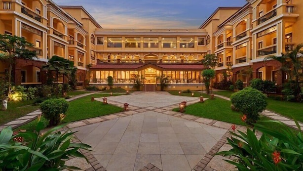 Un hotel con un patio central, varios balcones y un jardín bien cuidado.