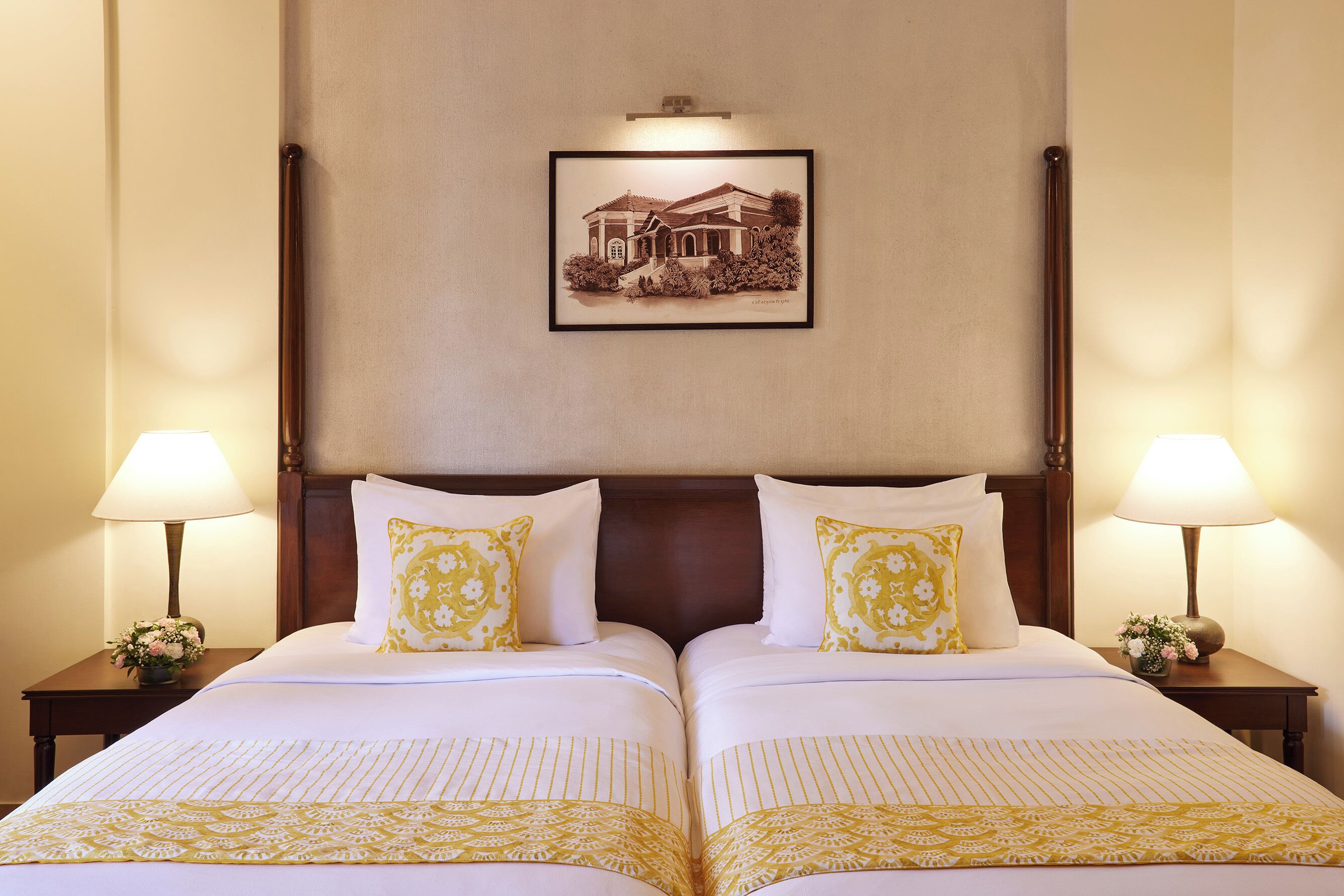 A hotel room with two beds, a framed picture on the wall, and lamps on either side.