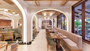 Un restaurante espacioso con techos altos, vigas de madera y una larga zona de comedor con mesas y bancos.