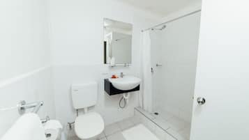 Casa de banho moderna com sanita, lavatório e chuveiro.