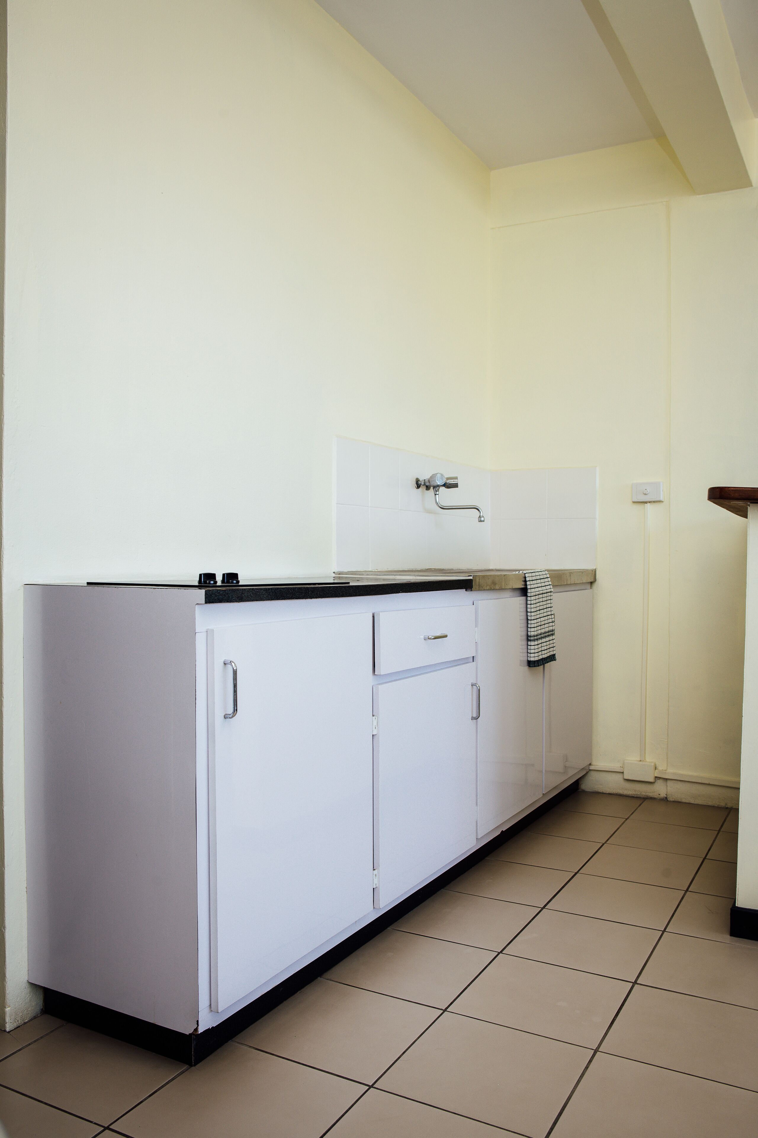 Una cocina con gabinetes blancos, una encimera y suelo de baldosas.