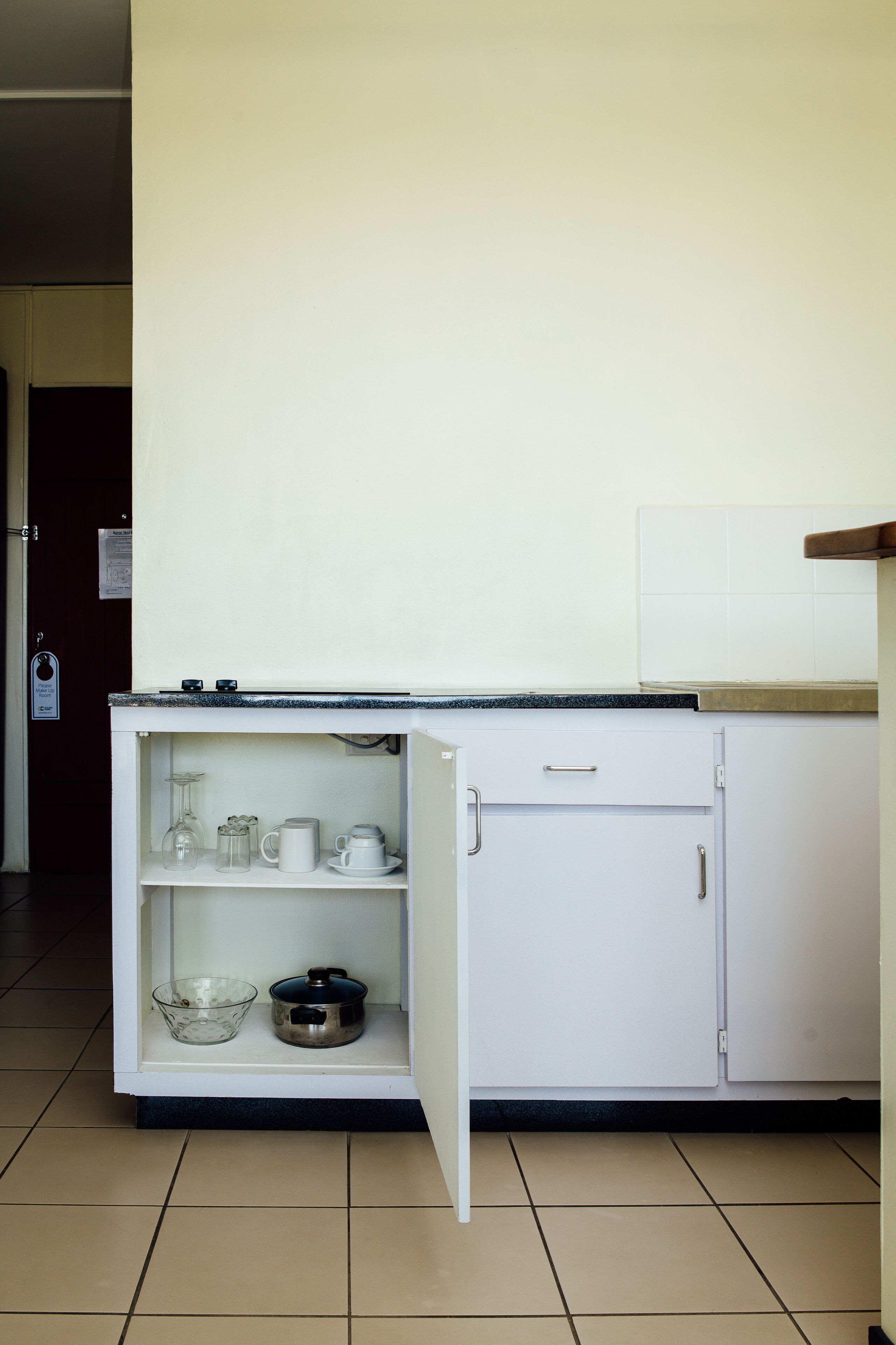 A kitchenette with a countertop, a small cabinet, and a tiled floor.