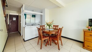 A compact kitchen with a dining area, a wooden cabinet, and a small TV on a wooden stand.