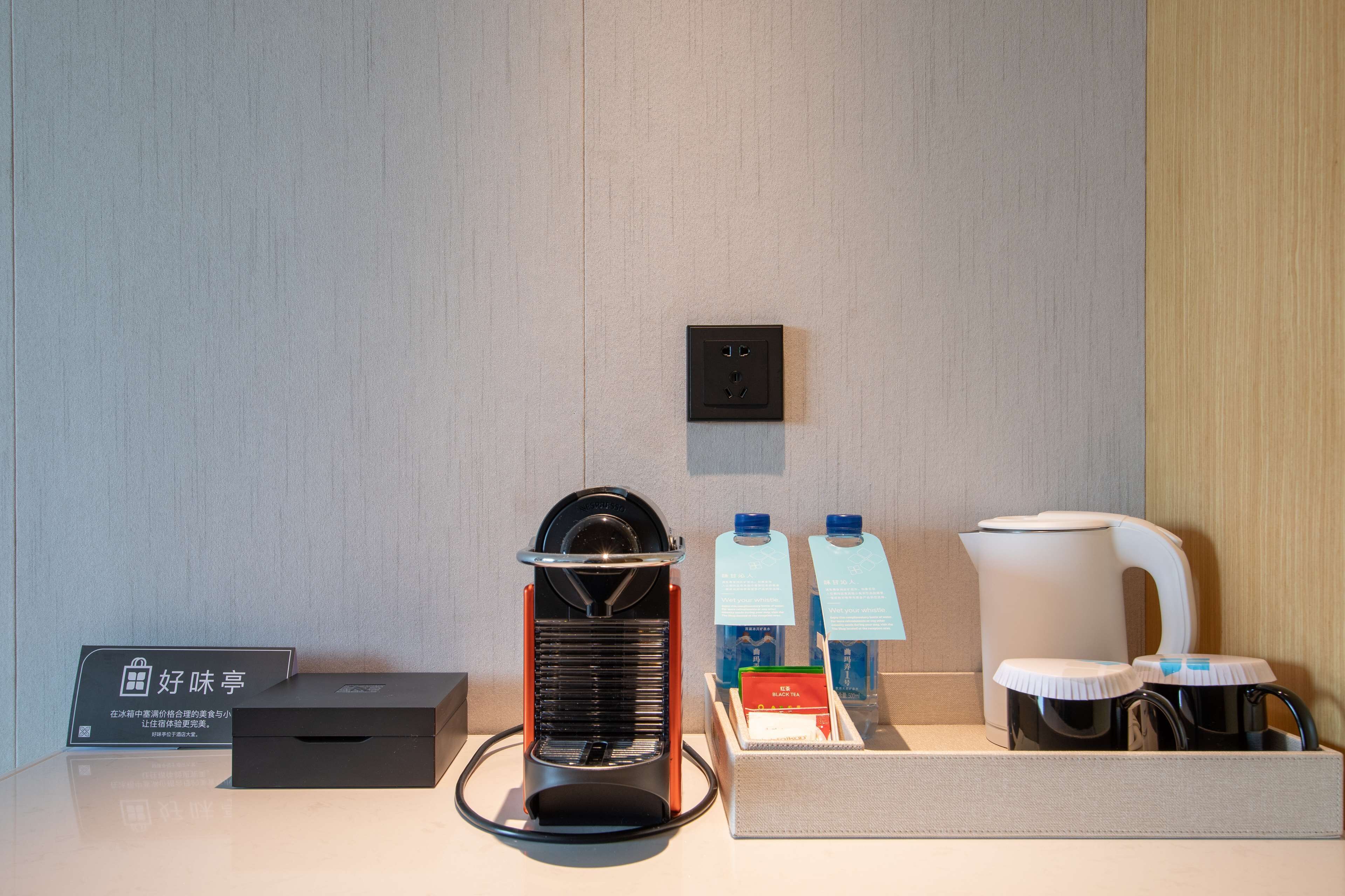 Habitación de hotel con cafetera, hervidor de agua y botellas de agua sobre la encimera.