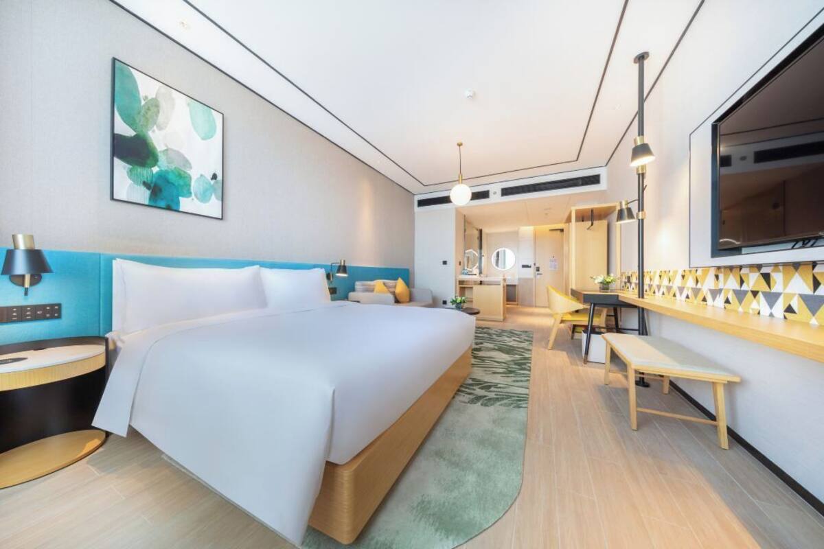 Une chambre d’hôtel moderne avec un grand lit, des tables de chevet, un bureau et un miroir.