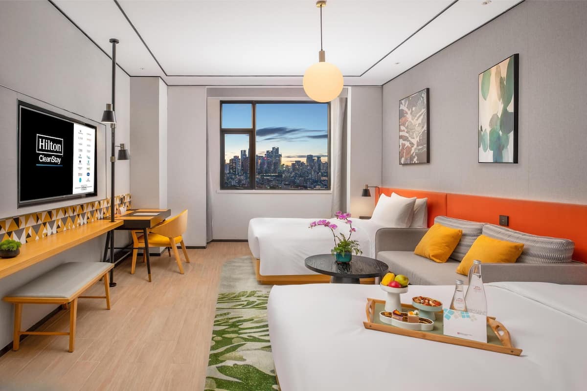 Une chambre d’hôtel moderne avec vue sur la ville, un bureau avec un ordinateur, un canapé et un lit.