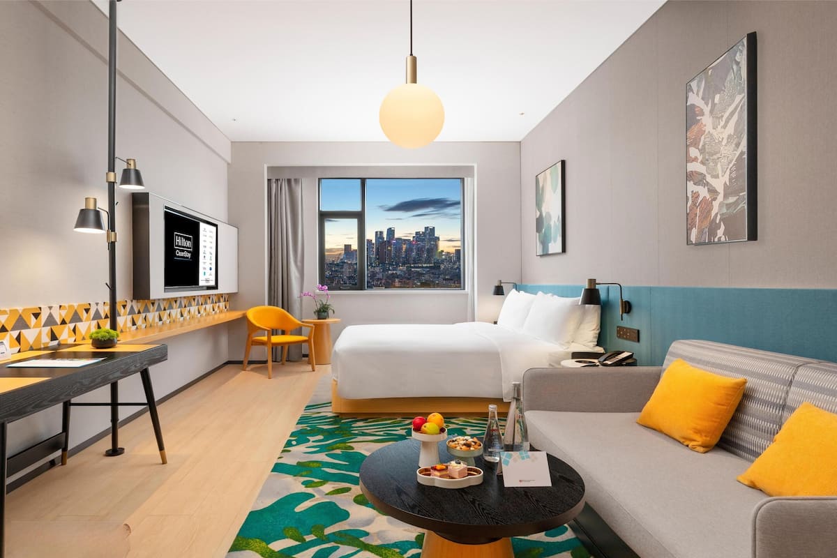 Une chambre d’hôtel moderne dotée d’un grand lit, d’un canapé, d’une table à manger et offrant une vue sur la ville.