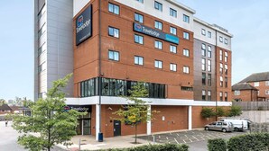 Een Travelodge hotel met een modern design, herkenbaar aan de bakstenen gevel en de vele ramen.