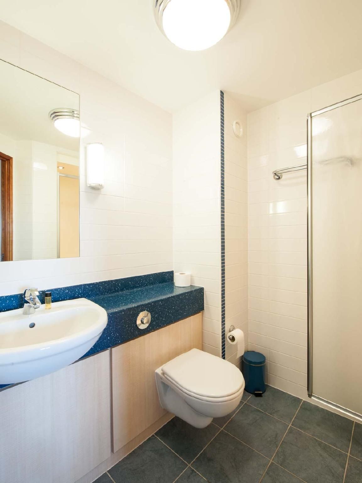 A bathroom with a white sink, a toilet, and a shower area.