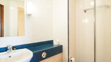 A bathroom with a white sink, a toilet, and a shower area.
