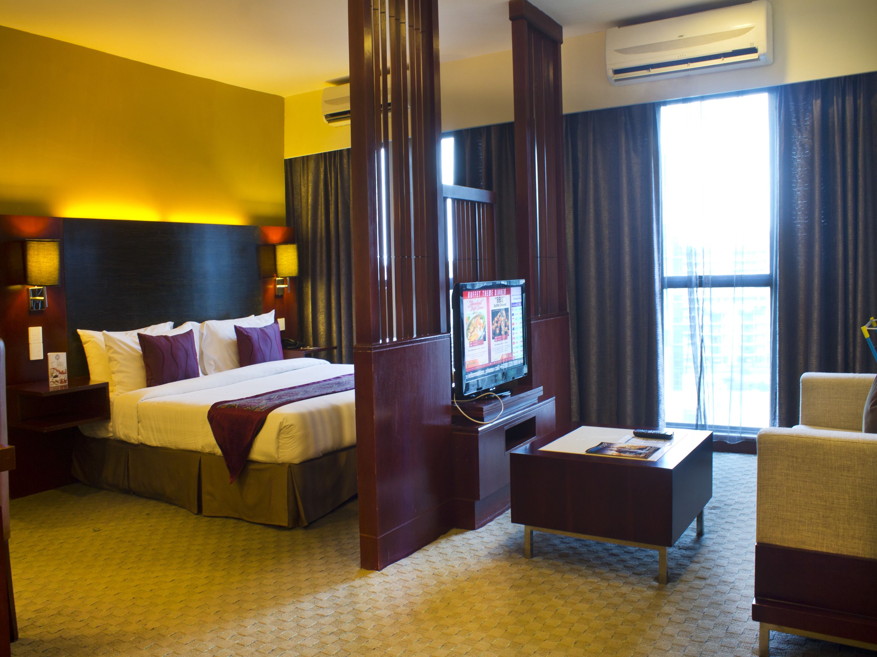 A hotel room with a large bed, a television, a desk, and a chair.