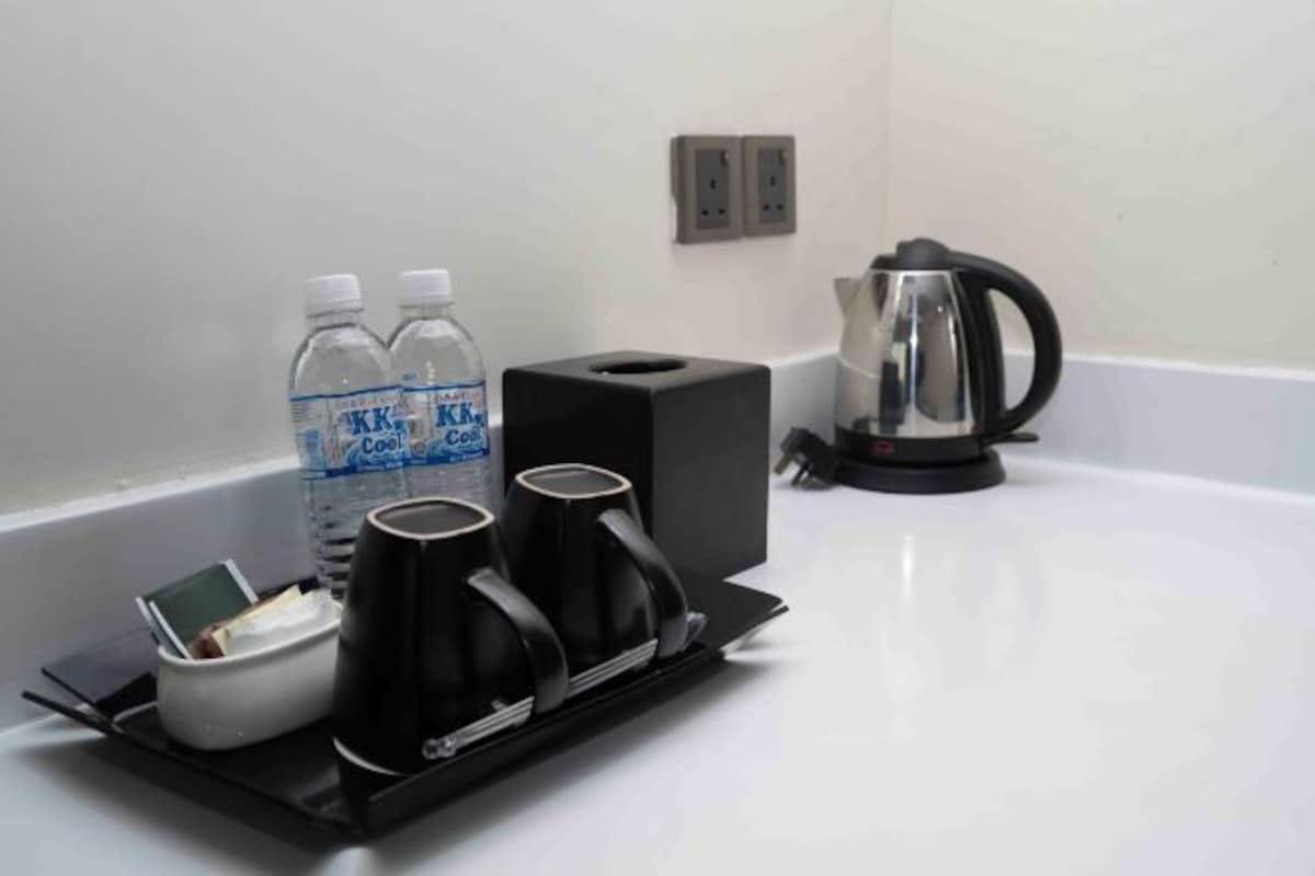 A hotel room's kitchenette with a coffee maker, two water bottles, a kettle, and a tray.