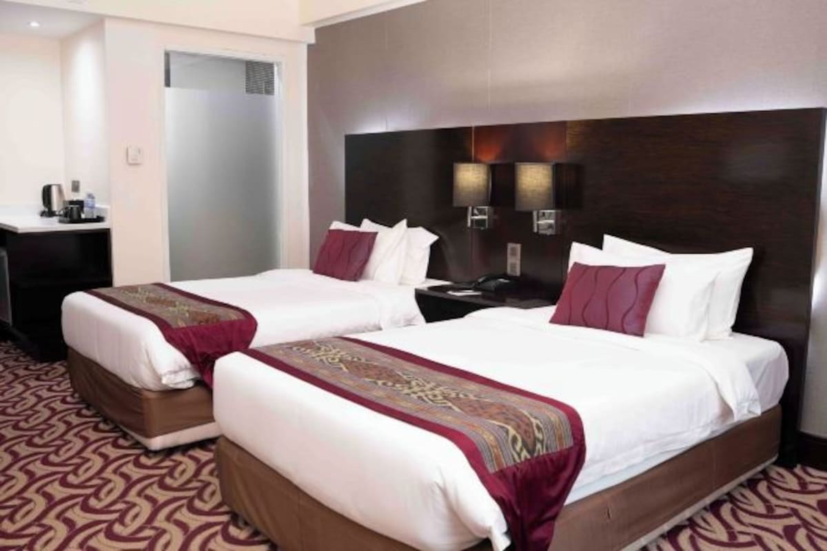A hotel room with two beds, a desk, and a wardrobe.