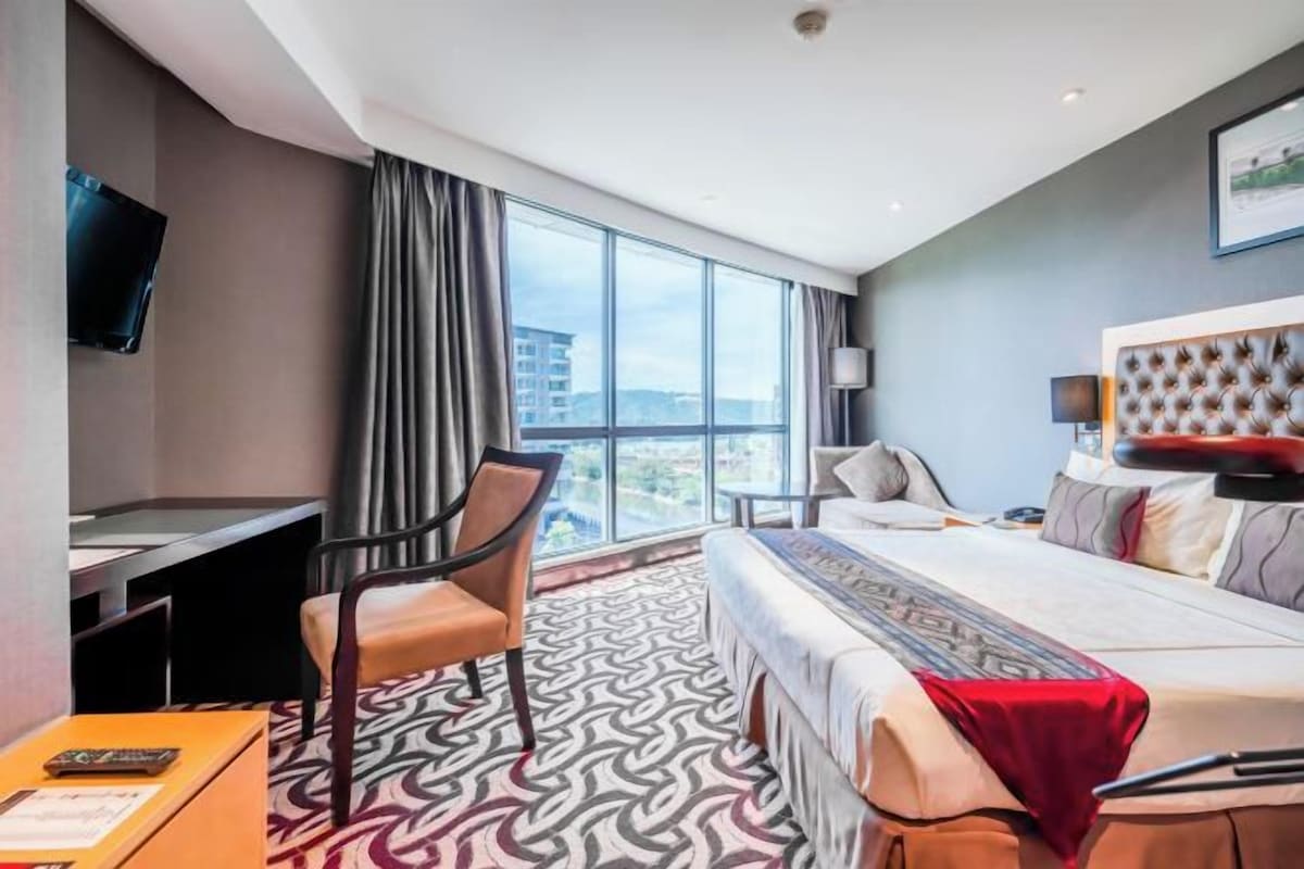 Een hotelkamer met een groot bed, een bureau, een stoel en een televisie.