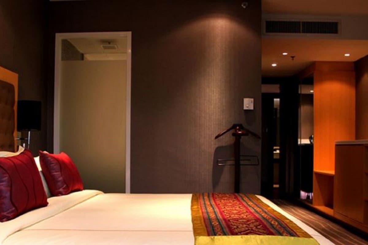A hotel room with a bed, a wardrobe, a desk, and a door leading to another room.