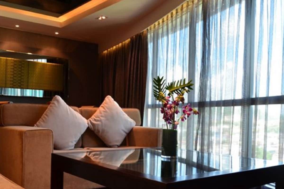 A modern hotel room with a sofa, a coffee table, and a large window with curtains.