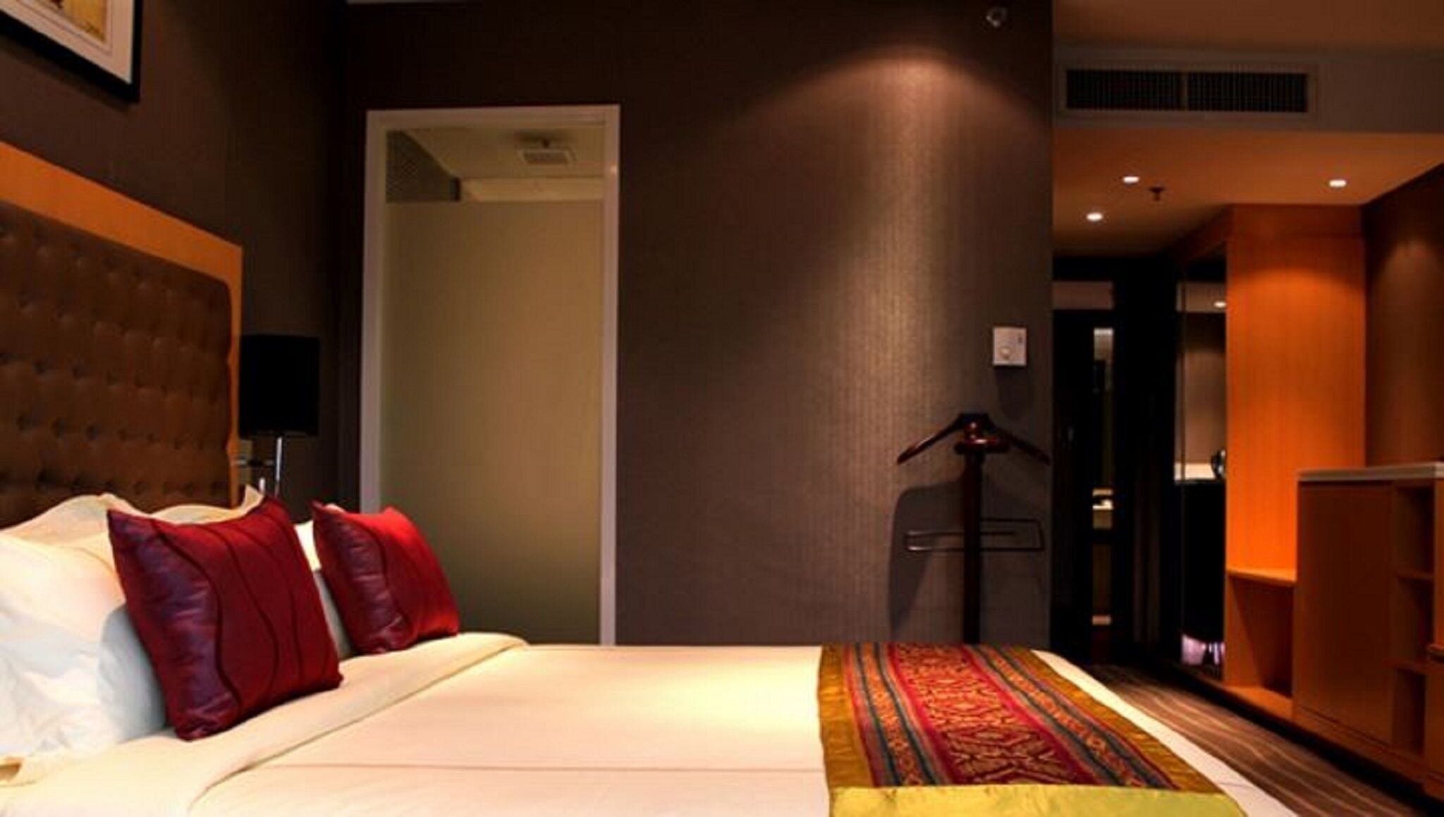 Een hotelkamer met een bed, een kledingkast, een bureau en een deur naar een andere kamer.