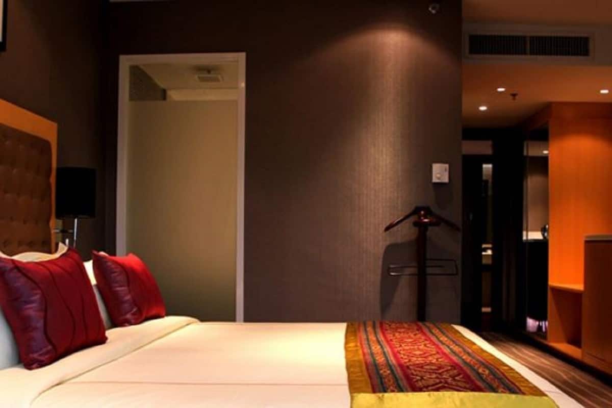 A hotel room with a bed, a wardrobe, a desk, and a door leading to another room.