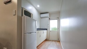 Una cucina compatta con frigorifero, forno a microonde e una finestra vista.