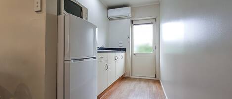 Una cocina compacta con refrigerador, microondas y ventana con vistas.