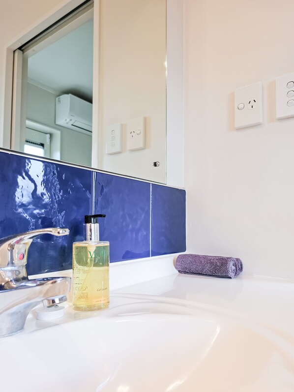 A bathroom with a white sink, a mirror, and a blue-tiled wall.