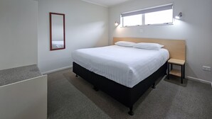 Una camera da letto con un letto, un comodino, uno specchio e una finestra.