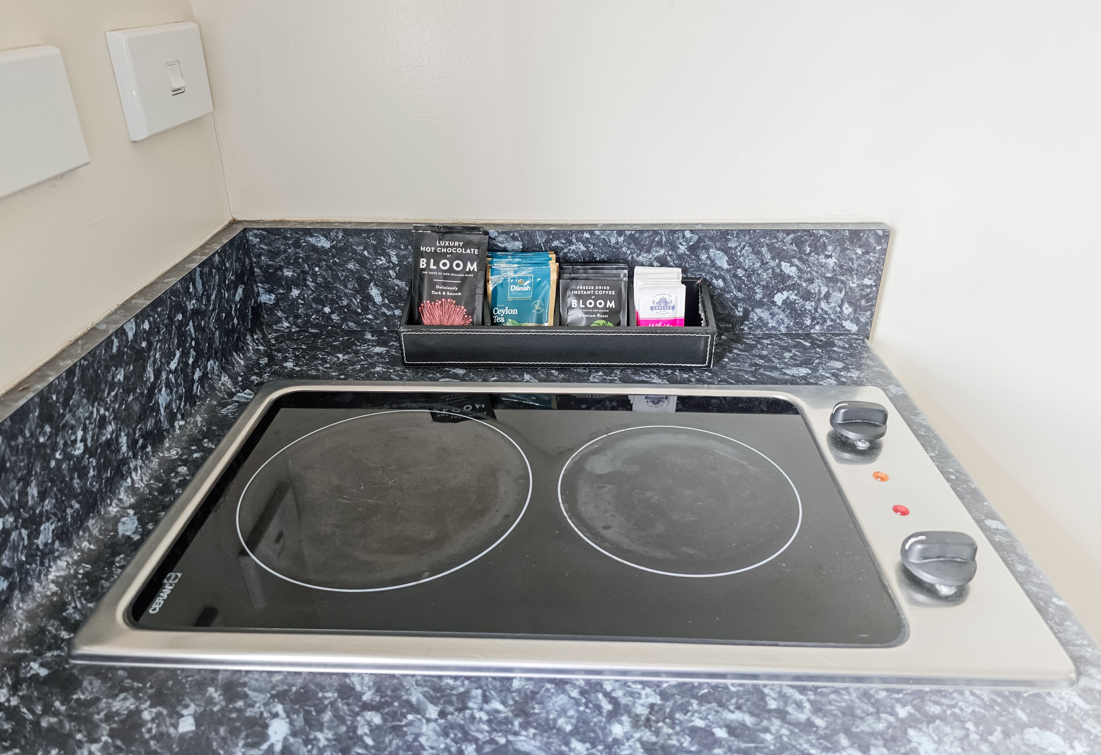 Uma cozinha com fogão elétrico duplo e um espaço para temperos com diversos produtos embalados.