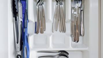A drawer with utensils and tools, including a knife, spoon, fork, and scissors.