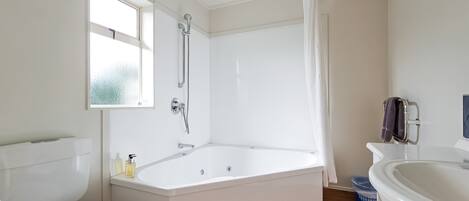 Un baño moderno con una bañera independiente, inodoro y lavamanos.